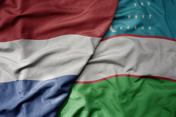 big waving national colorful flag of netherlands and national flag of uzbekistan .