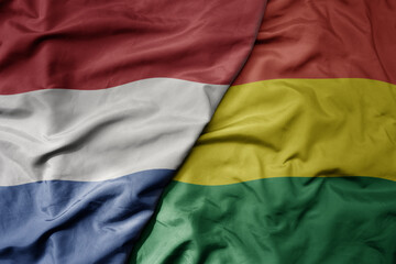 big waving national colorful flag of netherlands and national flag of bolivia .