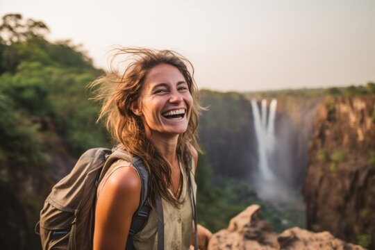 Medium shot portrait photography of a joyful girl in her 30s wearing a rugged jean vest at the victoria falls in livingstone zambia. With generative AI technology