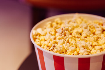 Popcorn box, close up. Movie theatre popcorn background. Entertainment concept. Cinema trendy. Movie snack. Salted popcorn in bucket. Fast food. 