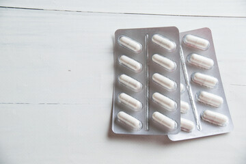 White pills in blister pack close-up on light table, background with copy space