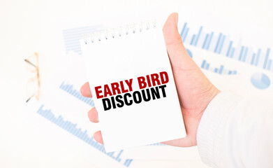 Businessman holding a white notepad with text EARLY BIRD DISCOUNT, business concept