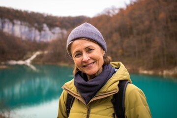Photography in the style of pensive portraiture of a happy mature woman wearing a thermal fleece pullover at the plitvice lakes national park croatia. With generative AI technology