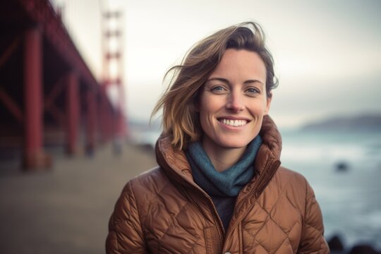 Environmental portrait photography of a grinning girl in her 30s wearing a quilted insulated jacket at the golden gate bridge in san francisco usa. With generative AI technology