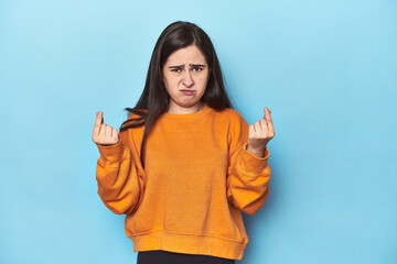 Young Caucasian woman on blue backdrop showing that she has no money.