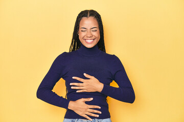 Young Indonesian woman on yellow studio backdrop laughs happily and has fun keeping hands on...