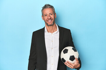 Caucasian football coach, middle-aged on blue set happy, smiling and cheerful.