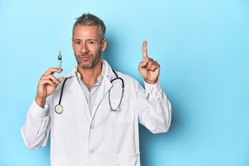 Doctor with a syringe on a blue studio background