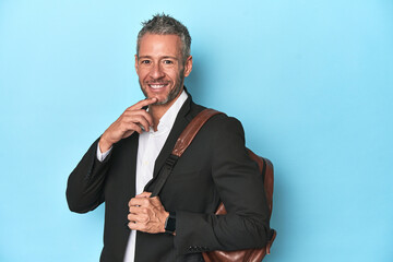 Businessman with a backpack on blue studio backdrop