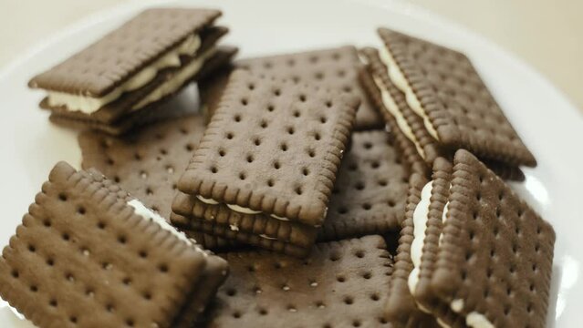 Triple chocolate biscuits with white filling are rotated on a turntable. Close-up.