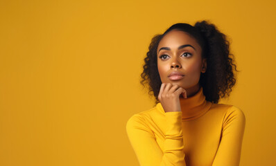 beautiful african american woman in yellow turtleneck looks away reflectively, studio image