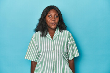 Fototapeta premium Young african american curvy woman shrugs shoulders and open eyes confused.