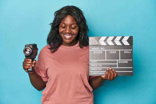 Creative curvy woman with film camera and clapperboard