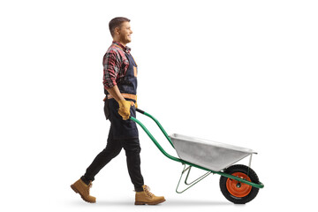 Full length profile shot of a gardener pushing an empty wheelbarrow