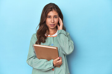 Young teacher holding notebooks, imparting knowledge covering ears with hands.