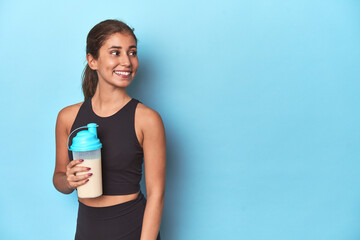 Young sportswoman with protein shake, ready for gym.