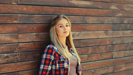 Portrait of beautiful caucasian blonde young woman in casual checkered shirt in the city