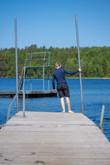 Young man stading on a pier about to jump in the water.