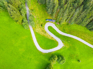 Curvy country road in the alpine mountain forest. Aerial view from drone.
