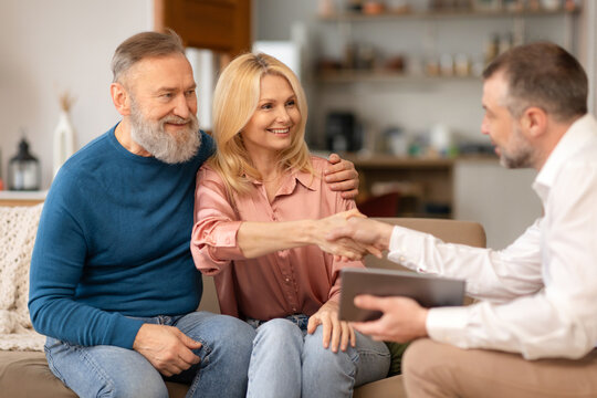Cheerful Senior Spouses Shaking Hands With Real Estate Agent Indoors