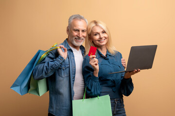 Cheerful elderly man and woman shopping on Internet, using laptop