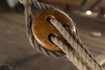 detail of the rigging of an old sailing ship, a wooden triple deadeye block with lanyard