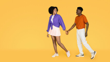 Cheerful millennial black lady in casual holding boyfriend hand, leads, enjoy date
