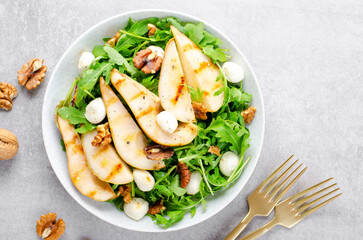 Grilled Pear Salad, Salad with Pear, Arugula, Mozzarella Pearls, Walnuts and Dressing over Bright Background