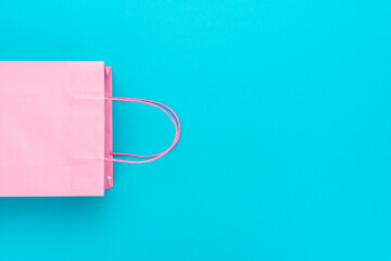 Flat lay photo of pink bag. Summer sale concept with copy space. Shopping paper bag on the turquoise blue background.