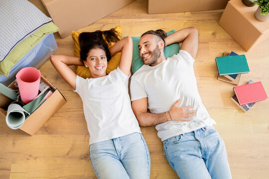 Happy couple lying on floor in new apartment, top view