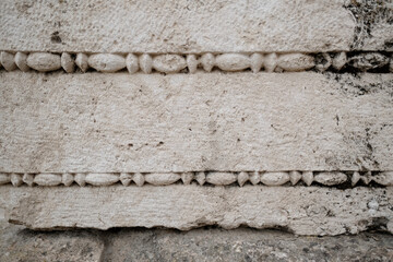 Closeup of beaded carvings along the edge of a block, part of a grand, monumental Roman ruin at...