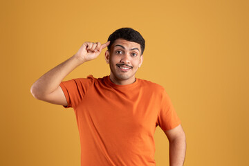 Excited brazilian man smiling, pointing to head with one finger, great idea or thought, good memory