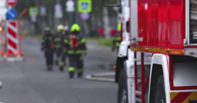 Group of fire men in uniform during blaze, fire fighting operation in the city streets, firefighters with the fire engine truck fighting vehicle in the background, emergency and rescue, slow motion