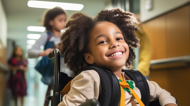 Photo captures the spirit of an African American elementary school student with a disability who is beaming with joy while sitting in a wheelchair in a school hallway.