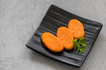 Carrot cutlets with parsley, on a serving plate. Light grey background. Top view. Copy space