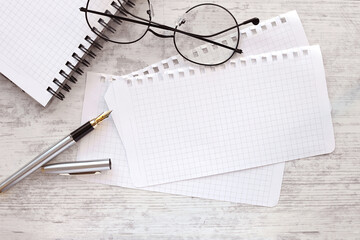 pages on the table.glasses and a white pen.