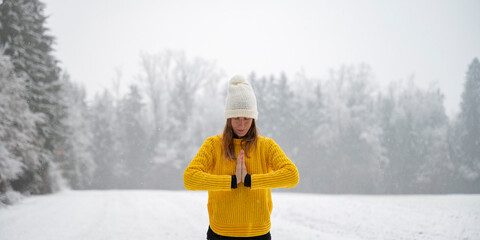 Peaceful young woman meditating or praying in winter nature with her palms joined in front of her chest - 643807740