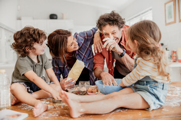 Young caucasian family being messy and having fun baking together in the kitchen