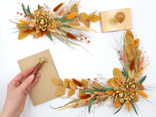 Flatley of yellow flowers on white background, beige envelope, hand holding seal, space for text, top view. Decor, welcome card. High quality photo