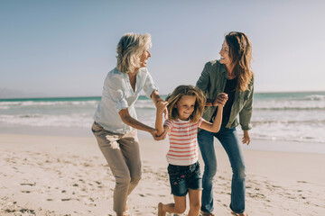 Multigenerational family having fun and walking on a sandy beach together