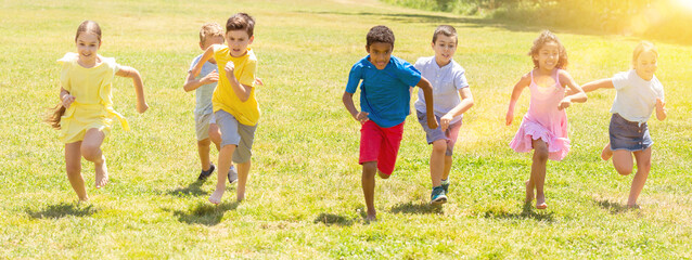 Group of happy kids running in race in the street and laughing in park
