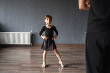 Child girl standing in black sport bodysuit in dancing studio during training posture. 4 5 years old preschool age. Healthy physical development 