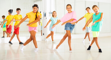 Fototapeta na wymiar Group of kids training modern dance moves together in studio.