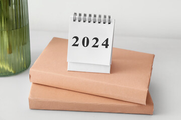 Calendar with figure 2024 and books on light table - obrazy, fototapety, plakaty