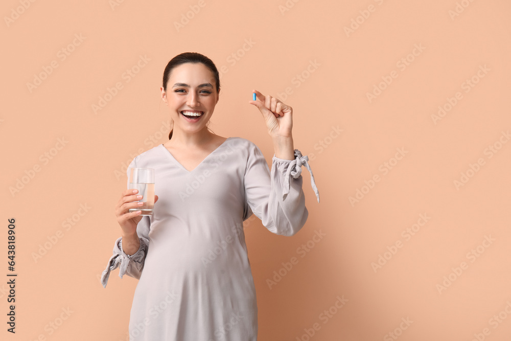 Sticker young pregnant woman with glass of water and folic acid pill on beige background