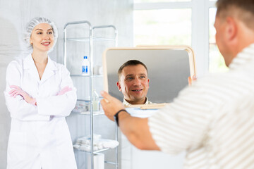 Obraz premium Young female doctor is satisfied with result of treatment and patient is satisfied with condition of facial skin, smoothed wrinkles