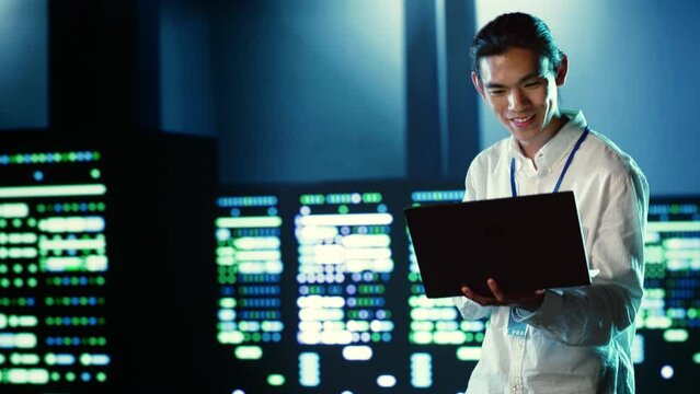 Skillful employee wandering around data center infrastructure providing processing resources for different workloads. Asian admin doing checkup on servers tasked with solving computational operations