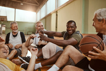 Diverse group of senior men taking a break from playing basketball in an indoor basketball gym