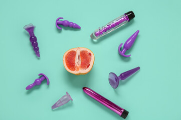 Composition with fresh half of grapefruit and toys on turquoise background. Sex education concept