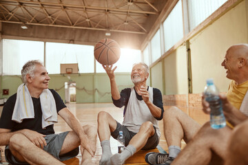Group of senior men taking a break from playing basketball in an indoor basketball gym